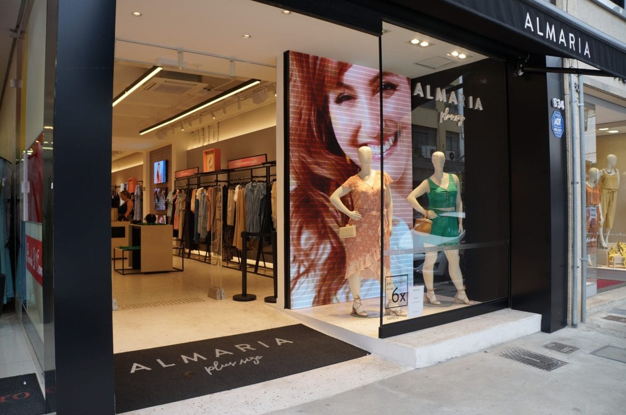 Painel de LED instalado em vitrine comercial, fotografado a partir da área de circulação do público.